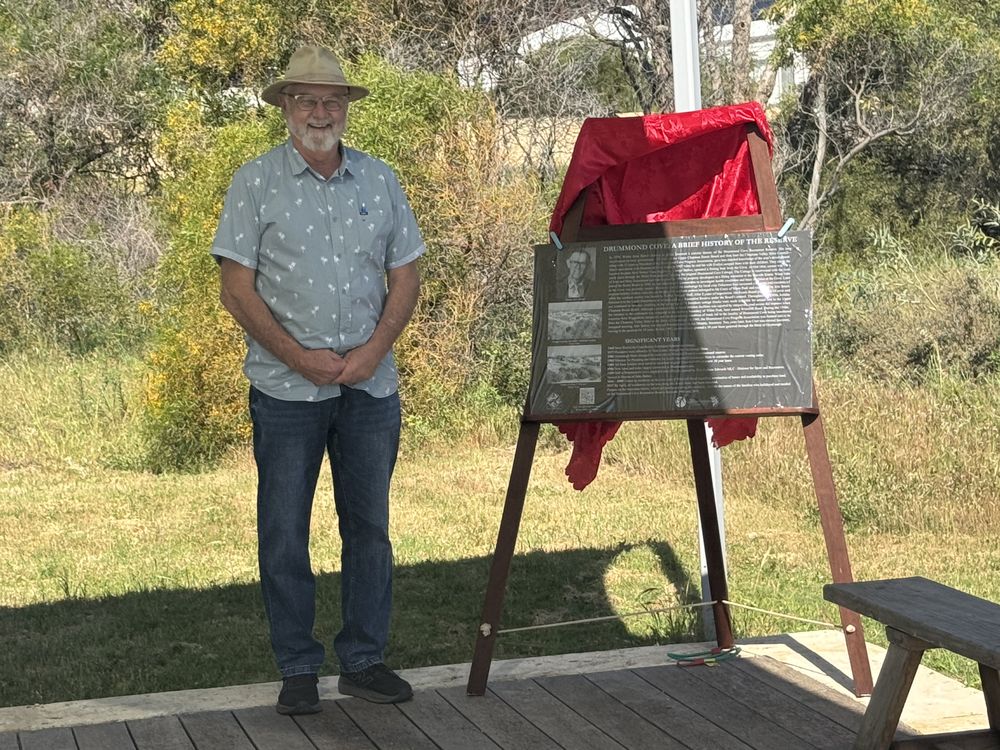 Mayor Jerry Clune beside the Drummond Cove interpretive plaque